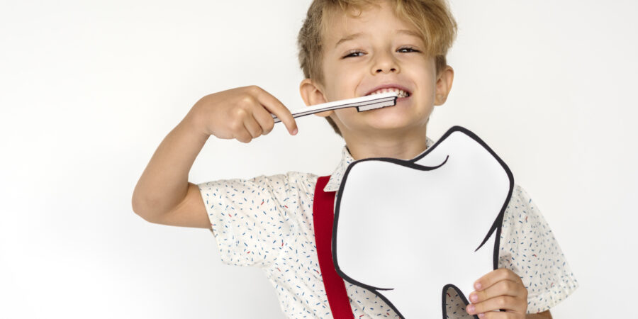 Smiling young boy holding a large white speech-bubble prop against a plain white background.
