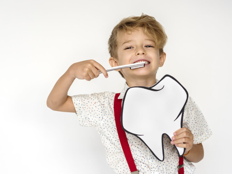 Smiling young boy holding a large white speech-bubble prop against a plain white background.